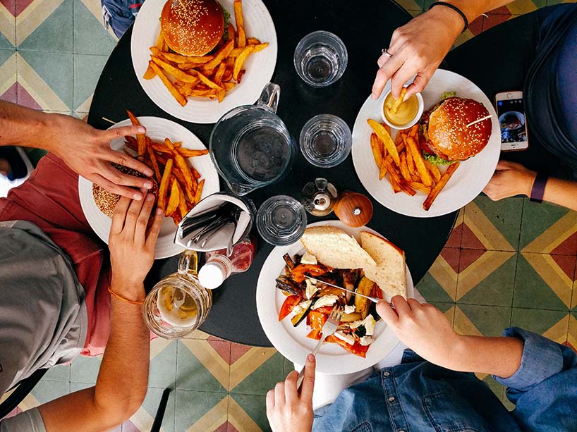 Plates of food that include burgers and fries.