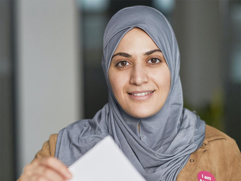 Woman in hijab places ballot in box