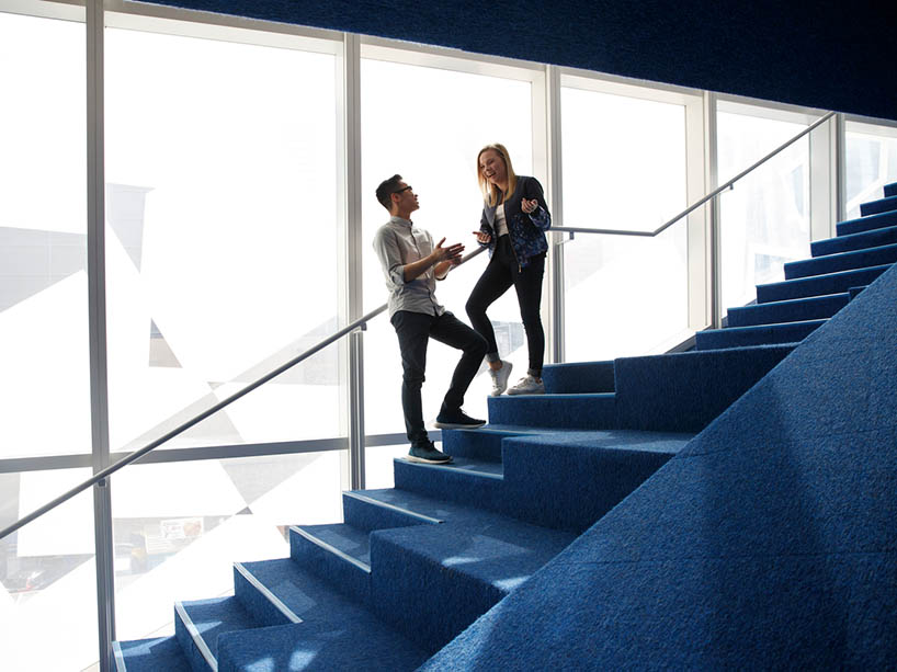 Two students talking on a staircase in the SLC