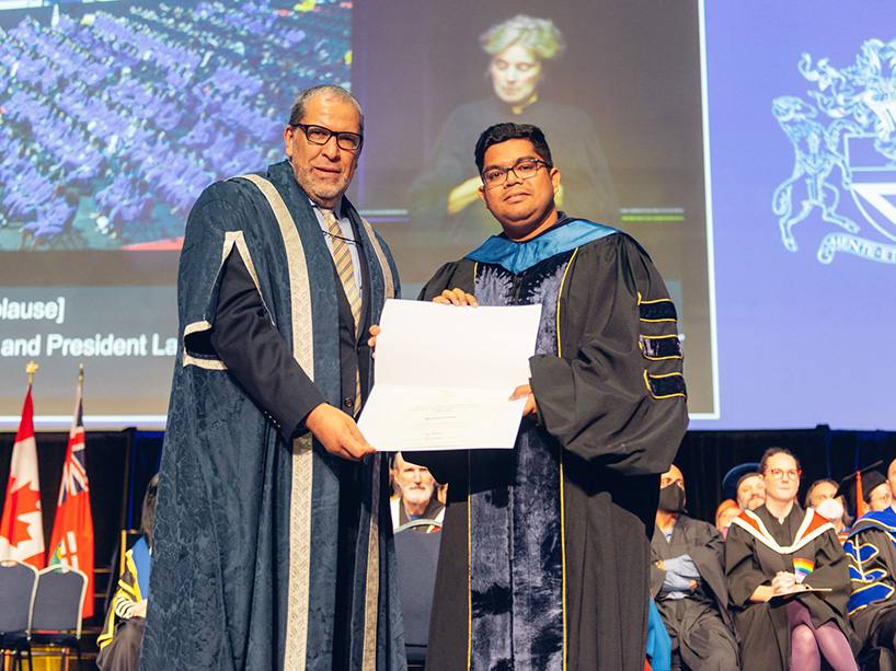 Md Amirul Islam holds his gold medal certificate while standing next to TMU President Mohamed Lachemi at the Fall 2022 convocation ceremony.
