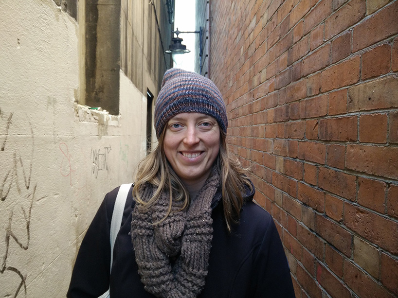 Photo of Stephanie Hill in a winter hat and scarf standing between two buildings in London, England, during her time as a visiting researcher at LSE.