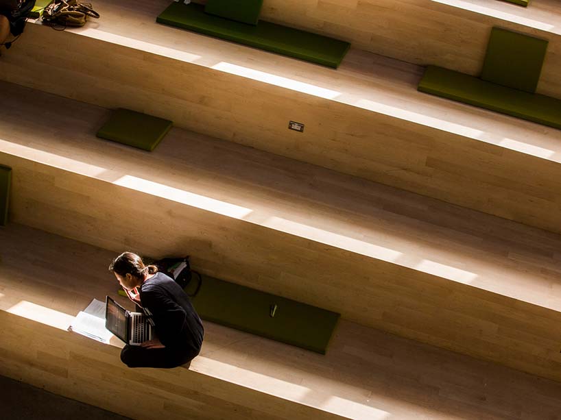 A student sits in the Student Learning Centre leaning over their laptop