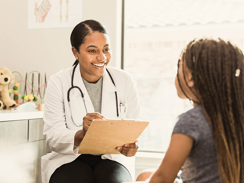 A doctor holding a clipboard and a pen sits with a child