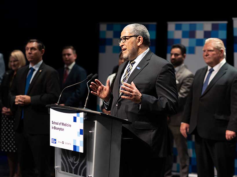 TMU President Mohamed Lachemi standing at a podium with Ontario Premier Doug Ford to his right.