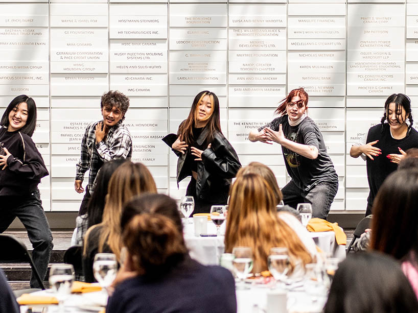 Five students dancing in front of attendees of the event.