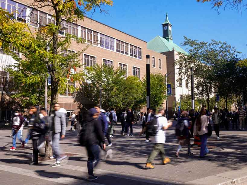 People moving about campus on a sunny day.