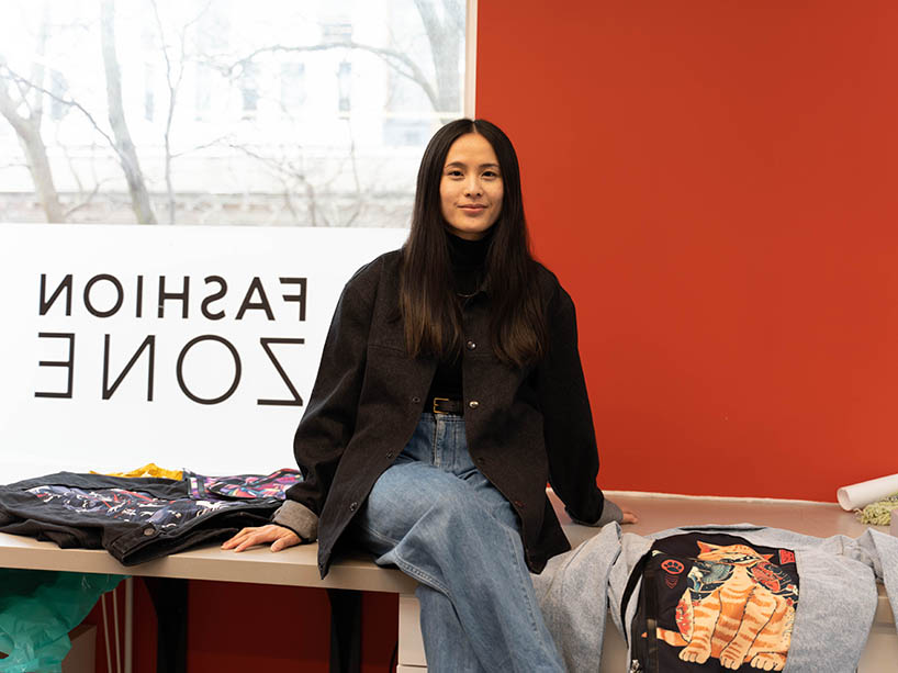Jane Souralaysack sitting on a counter in the Fashion Zone with her swappable jackets on display. 