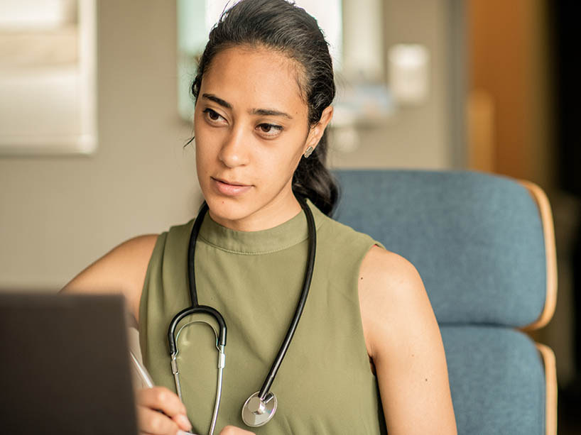 A medical student sitting in an office taking notes. 