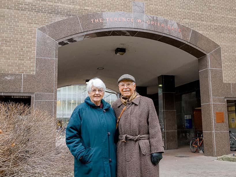 Terry Grier and Ruth Grier stand in front of the quad archway with text saying The Terence W. Grier Gate.
