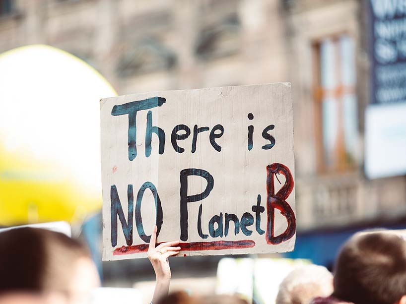  A person holds up a sign saying “there’s no planet B.”