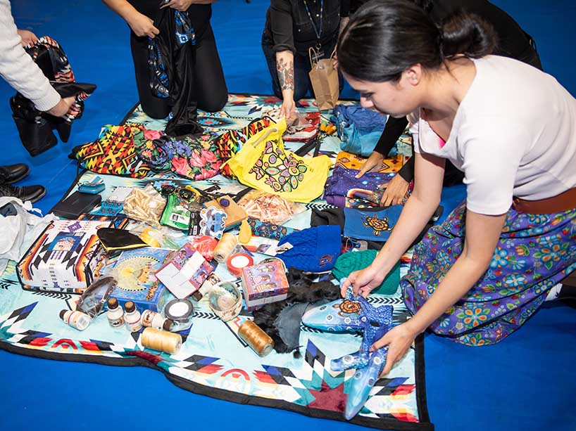 People place gifted items on a blanket on the floor.