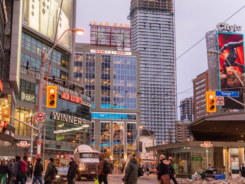 Busy Yonge and Dundas Sts. intersection showing 277 Victoria St building with the iconic Sam the Record Man sign atop.