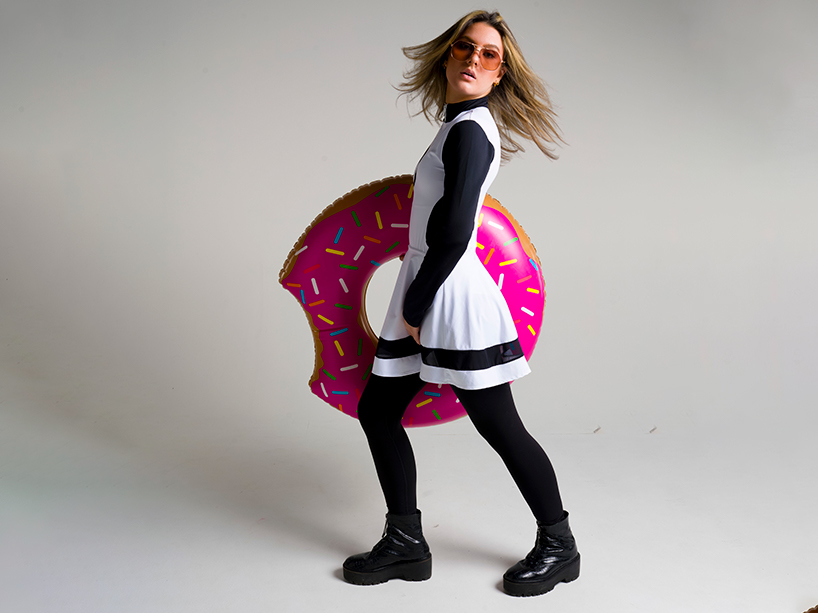 Young woman wearing skirted rashguard, leggings and boots while holding a pool inflatable