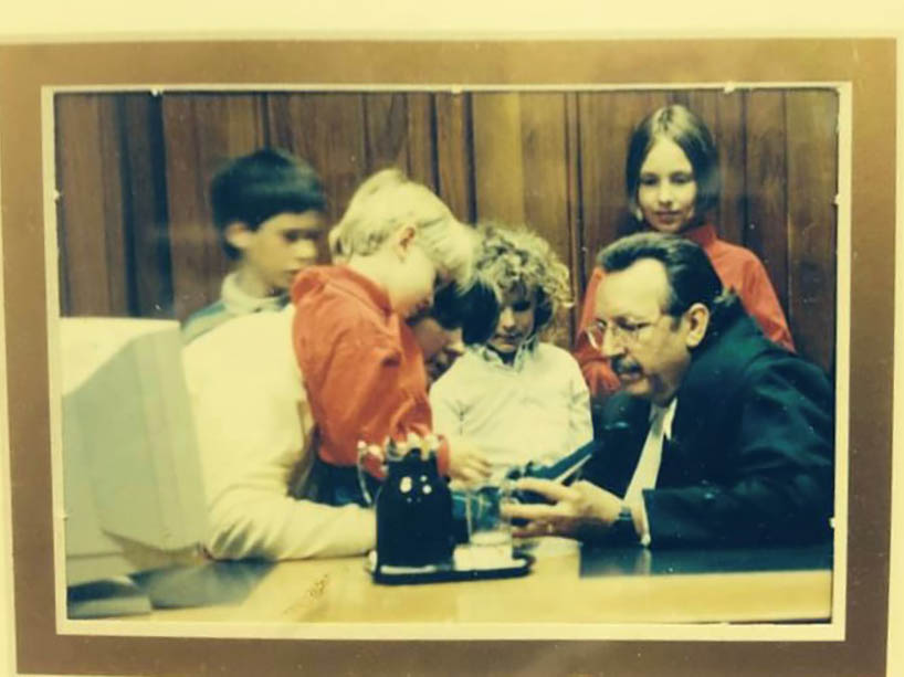 Children looking at an object held by a judge at a desk.