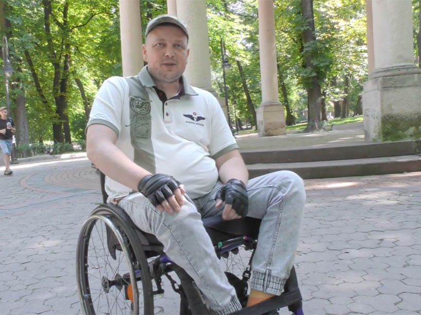 Sergei in a wheelchair, wearing a white hat and shirt. 