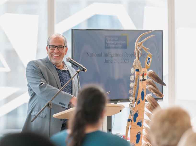 President Lachemi stands at a podium with a microphone smiling.
