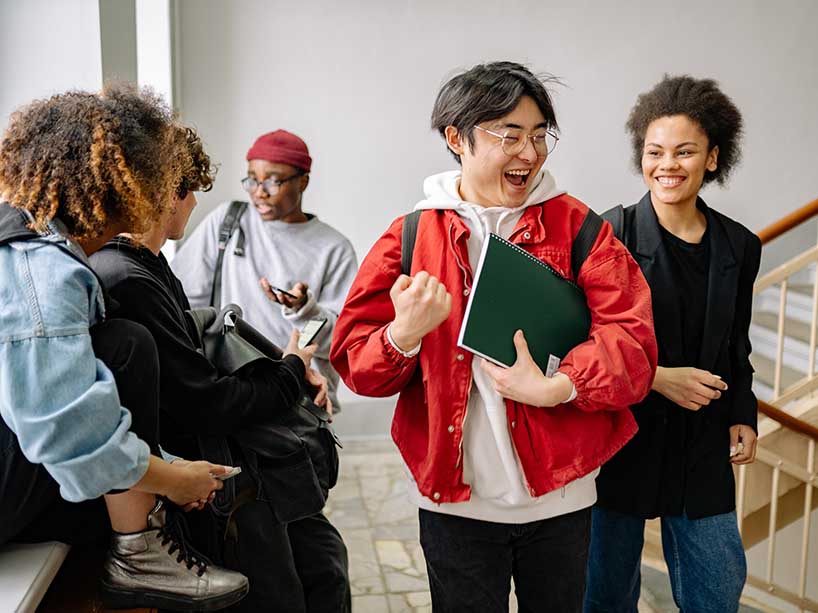 Laughing, smiling students socialize in hallway