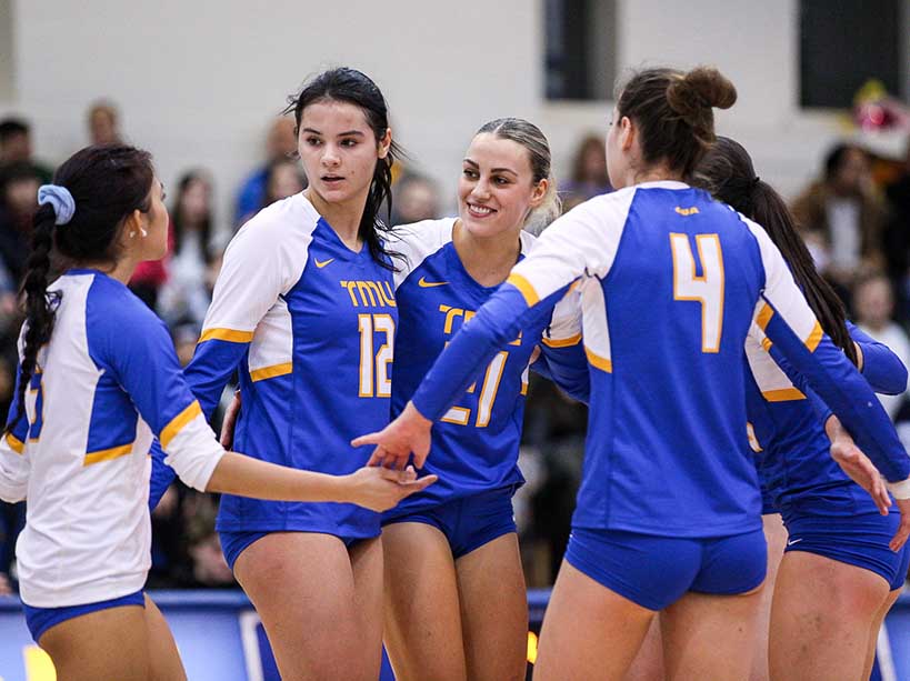 A group of women huddle during a volleyball game