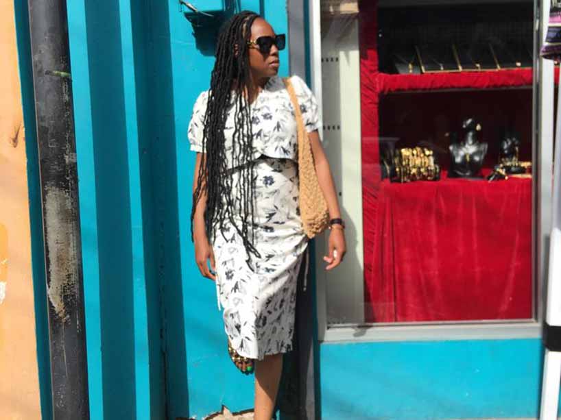 Tianna Makhurane against a blue wall in a white dress.