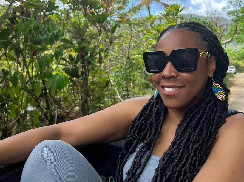 Tianna Makhurane wearing sunglasses with greenery in the background.