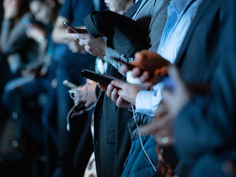 People stand in a long line with cell phones in hand.