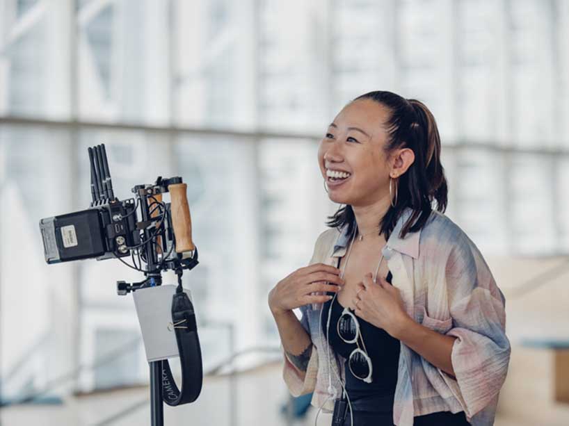 Melanie Chung stands behind a camera