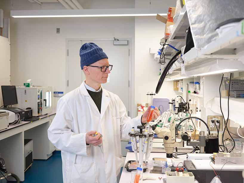 Dérick Rousseau in a lab coat looking at a test tube in a food research lab.