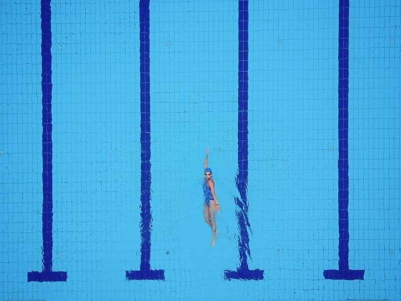 A birds-eye view of a person lane swimming in an empty pool