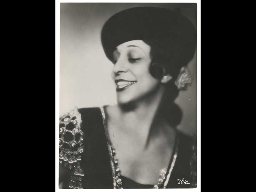 A black and white photo of a woman smiling and looking away from the camera