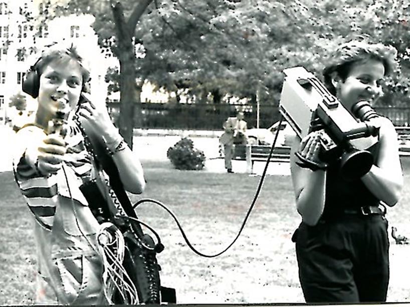 Two women holding camera gear outside.