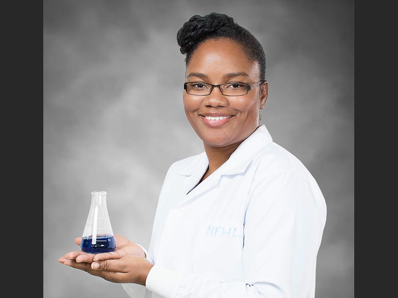 Syddonna Grizzle in a white lab coat holding a erlenmeyer flask. 