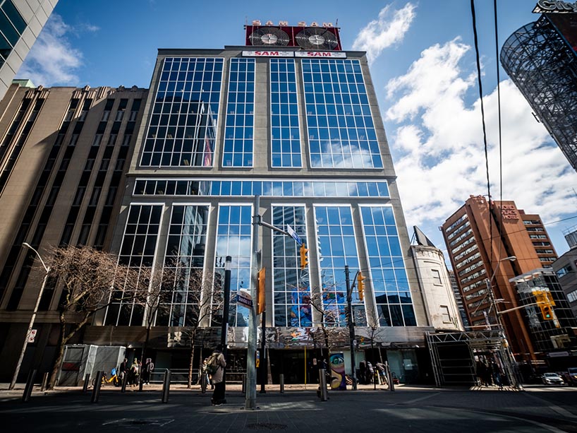 A building with glass windows surrounded by urbanscape.