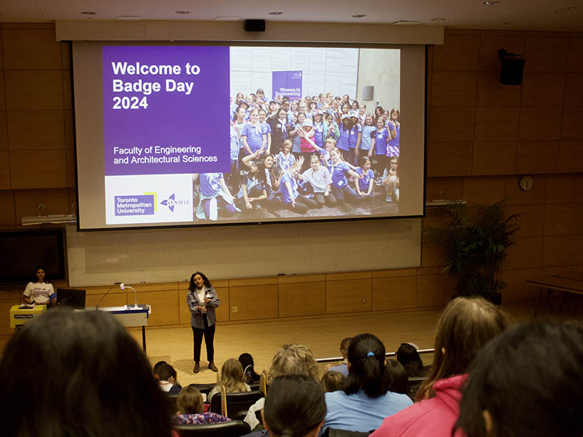 A woman speaks to a crowd of people in a lecture hall