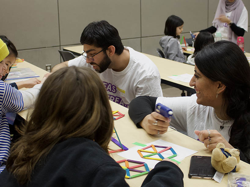 Two TMU students help Girl Guides with a ferris wheel craft