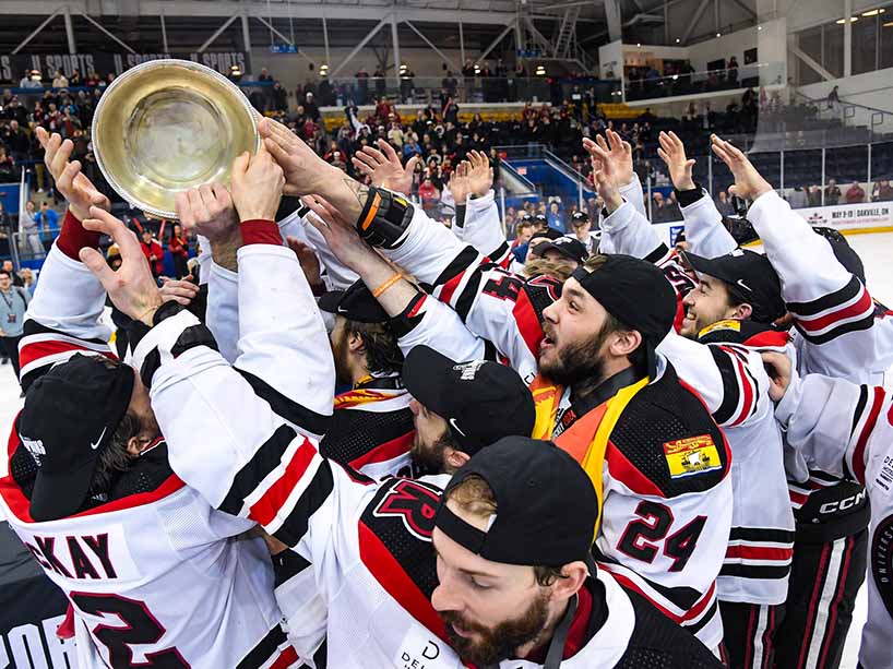 Players on the UNB Reds celebrate their championship win and hoist the David Johnston University Cup.