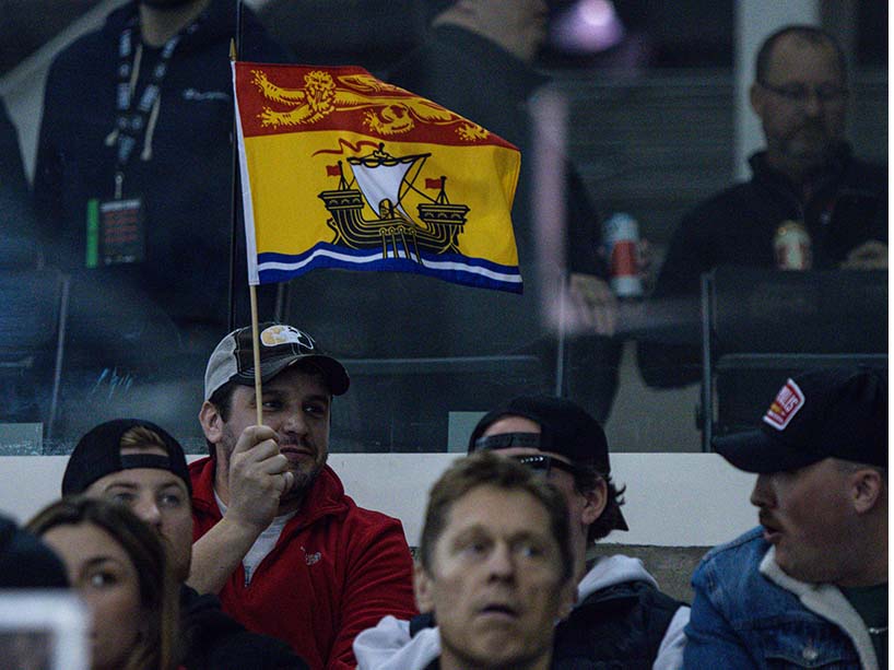 A fan waves the New Brunswick flag at the men’s hockey championship at TMU.