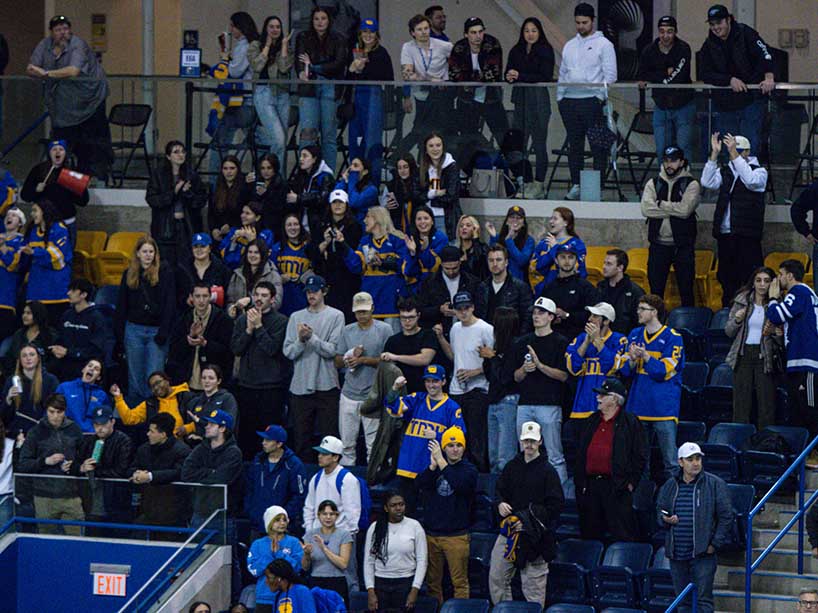 Fans in TMU Bold colours look out onto the ice from the stands.
