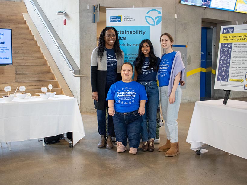 Four staff members standing next to a community tabling event.