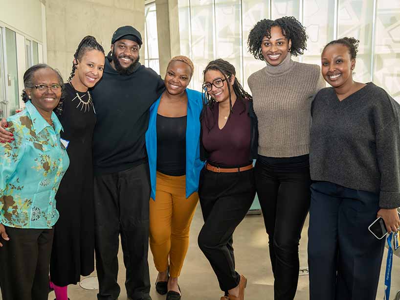  A group of people standing and smiling  at the camera. 