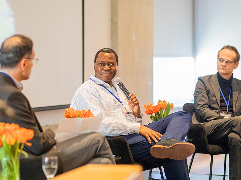 Three men engaged in conversation as one of them holds a microphone.