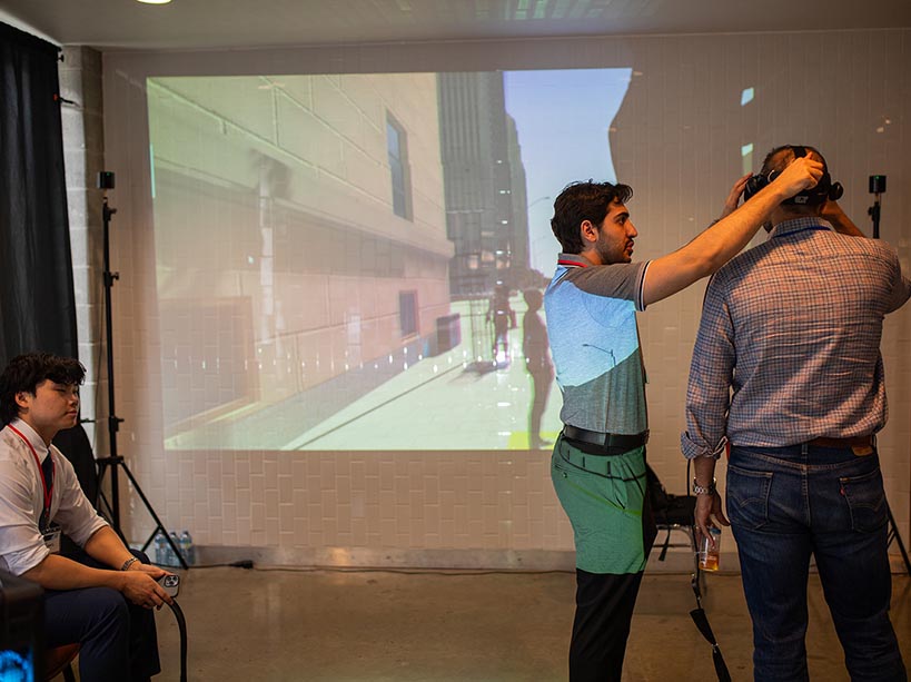 A TMU student helping a man wear an XR headset.