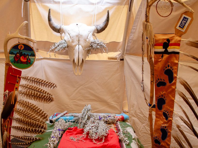 A buffalo skull is displayed in the teaching lodge, between two eagle staffs.