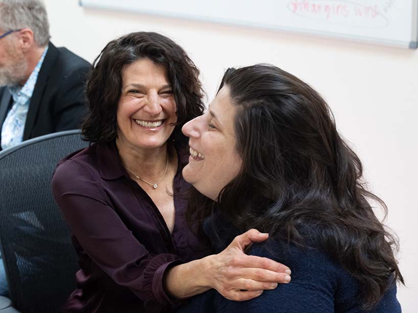 Two women smiling at each other in chairs. 