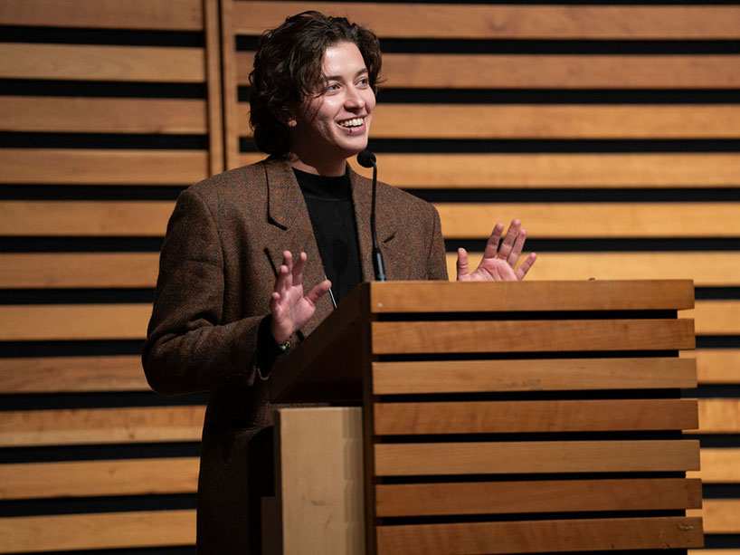 Finch Assadoullaev stands at a podium and delivers remarks.