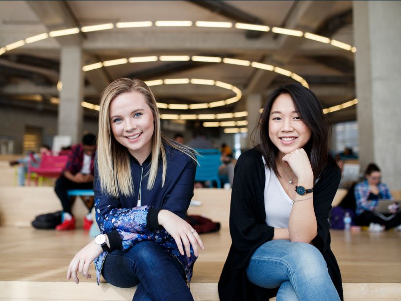 Two young women sitting on the SLC stairs