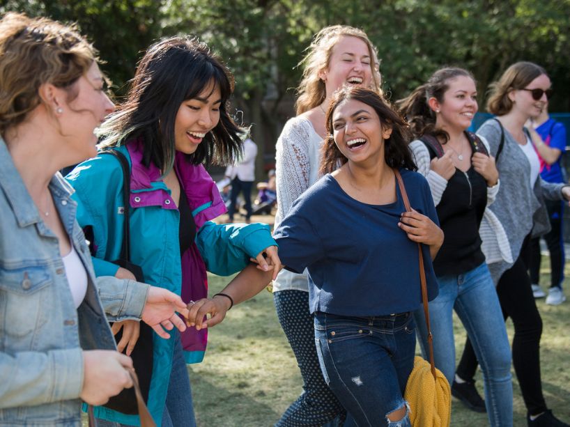 A group of female students laugh as they walk through the quad.
