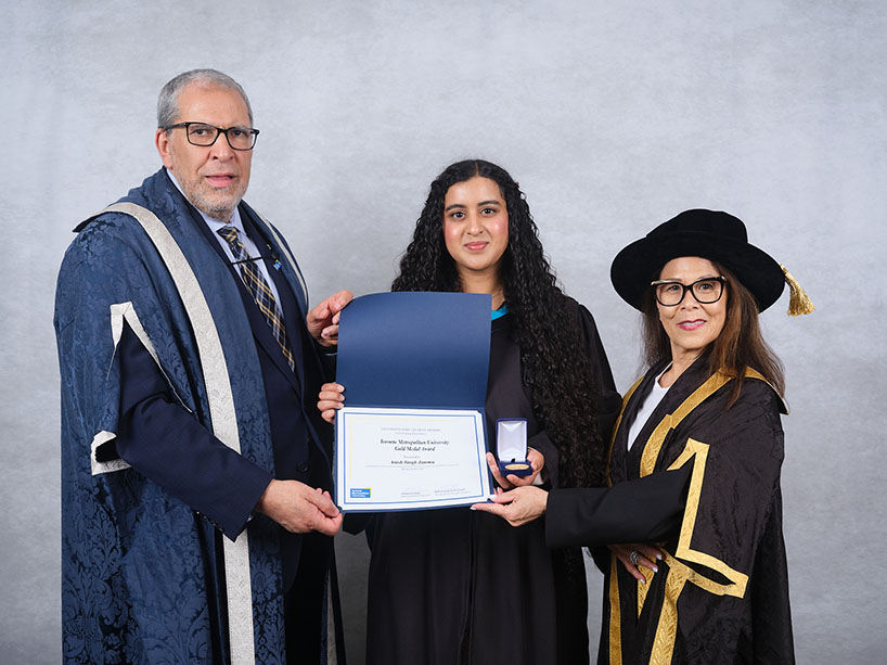 Three people wearing academic regalia pose for a photo with a certificate and medal.