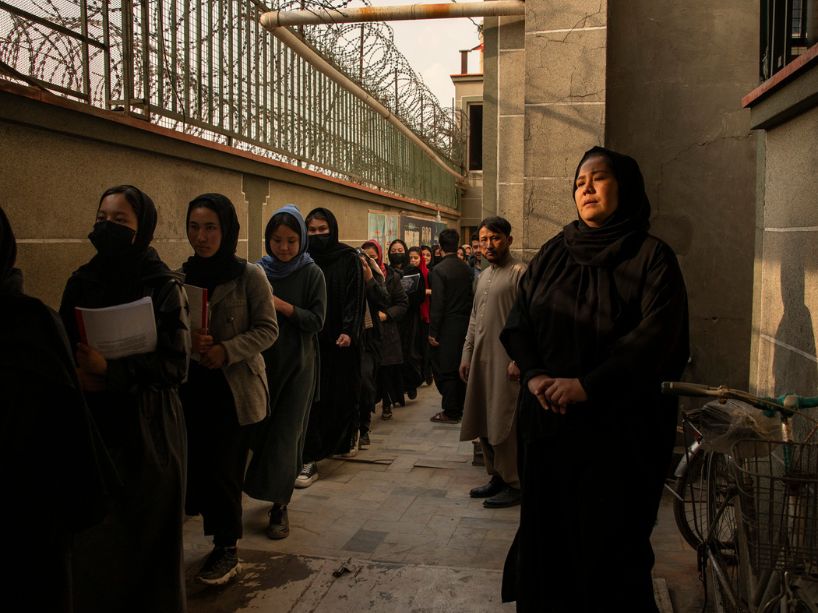 A dozen women in hijabs standing in line outside the private Kabul institute. 