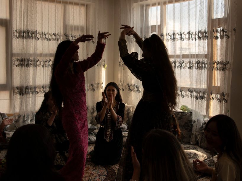 A group of young women are celebrating and dancing in an intimate living room. 
