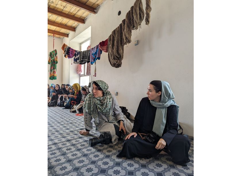 Kiana Hayeri, Melissa Cornet sitting on the ground side by side with a camera. 